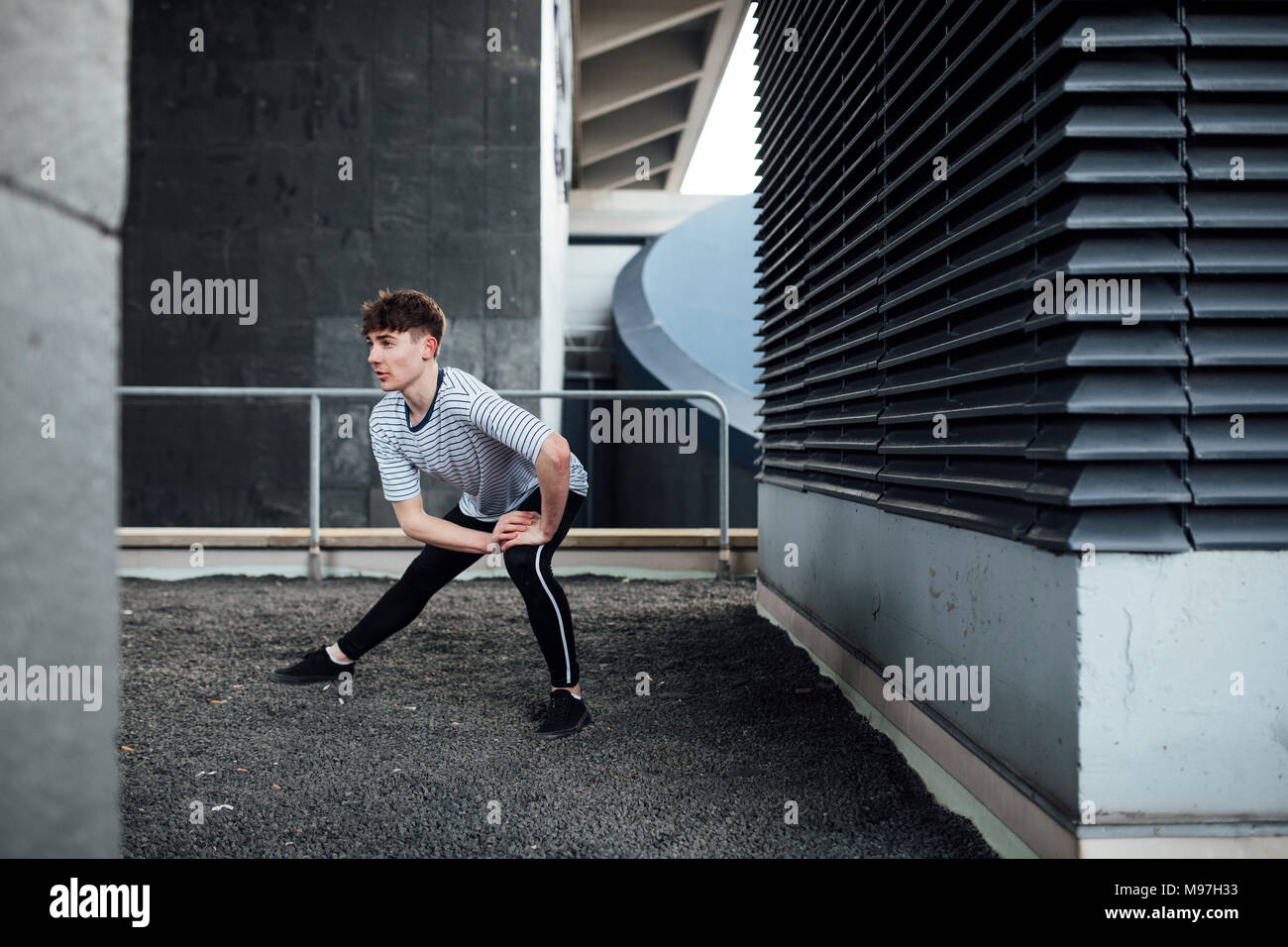 Freerunner è il suo stiramento dei muscoli delle gambe su un tetto. Foto Stock