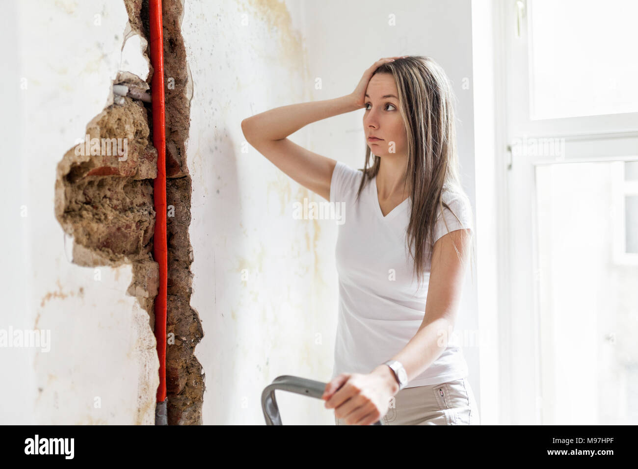 Donna che guarda la danno dopo un tubo di acqua di perdita a casa Foto Stock