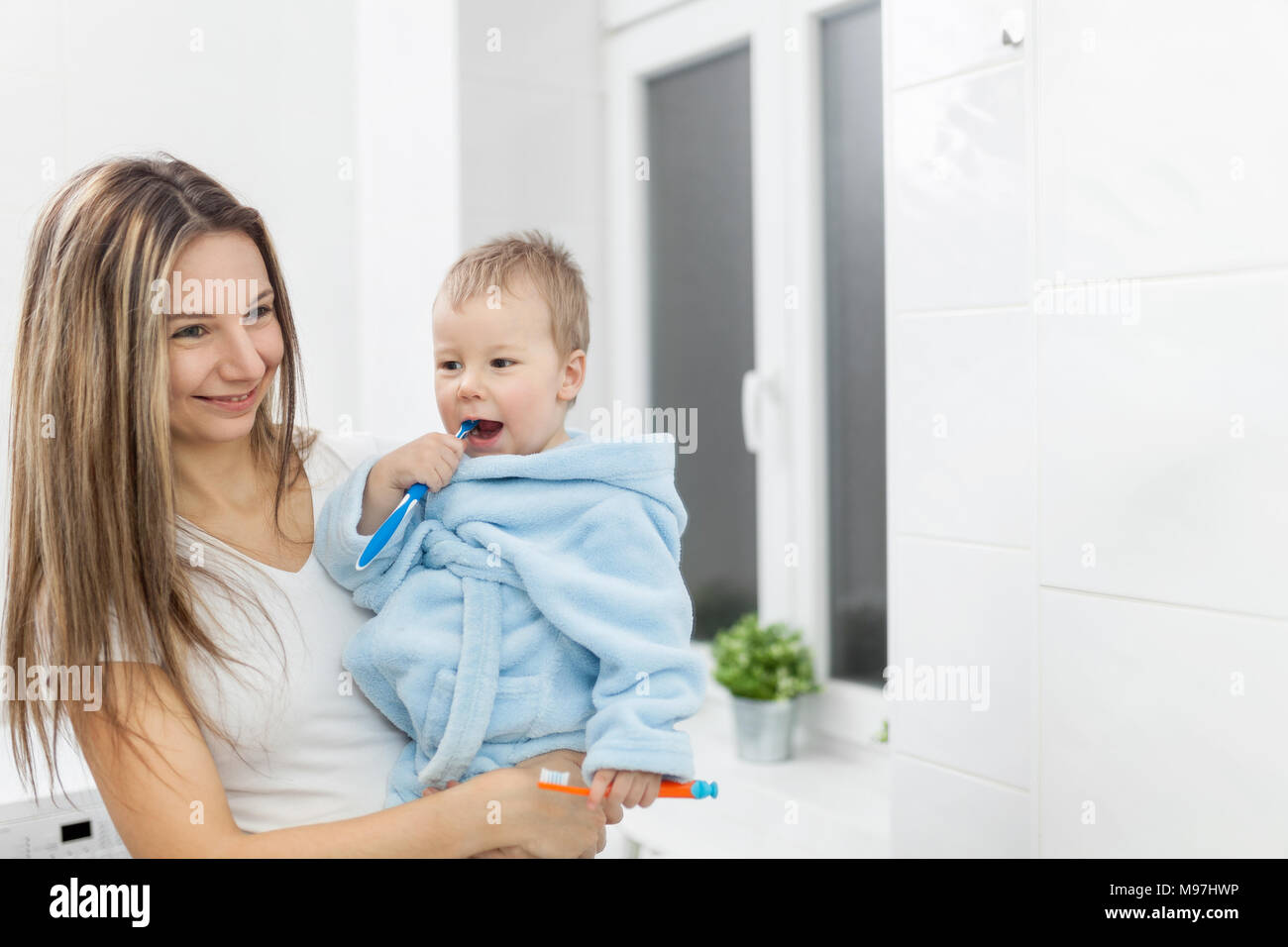 Felice madre insegnamento suo figlio come denti di bush in bagno Foto Stock