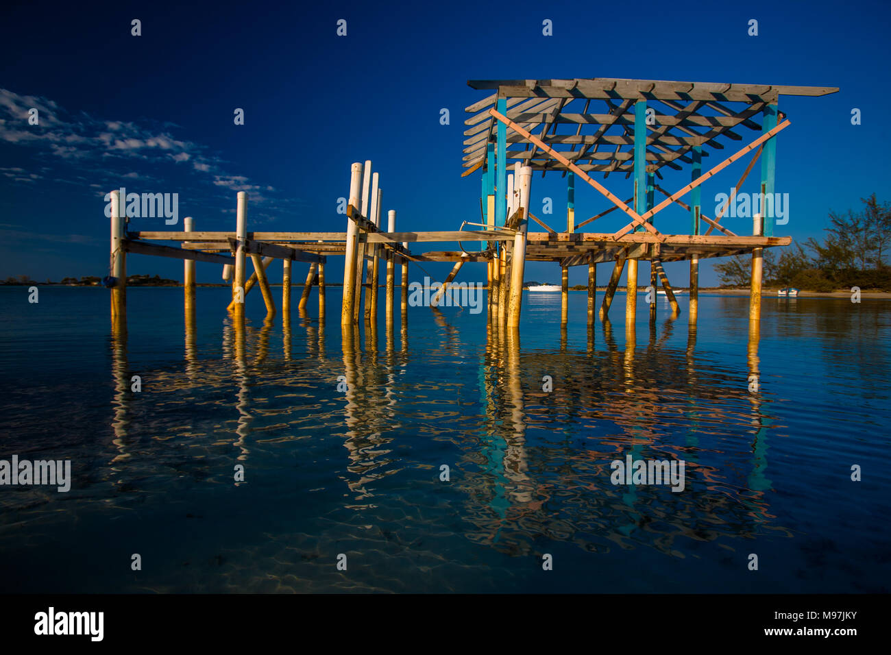 Pomeriggio notte riflette una bella immagine di un molo abbandonato sul litorale ancora delle Bahamas. Foto Stock