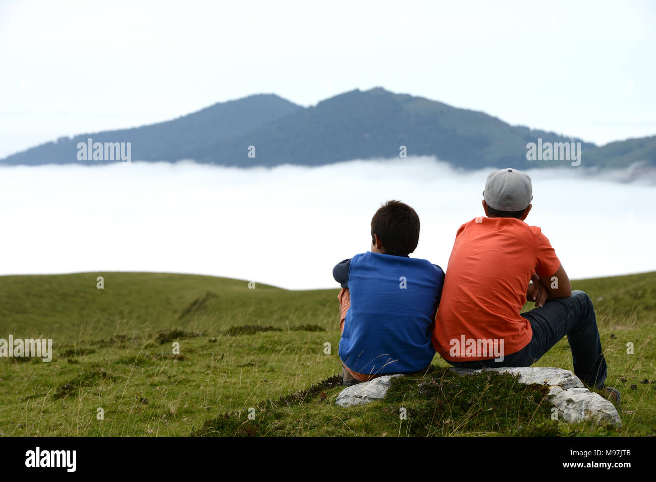 Bambini contemplando la montagna seduto su una roccia Foto Stock