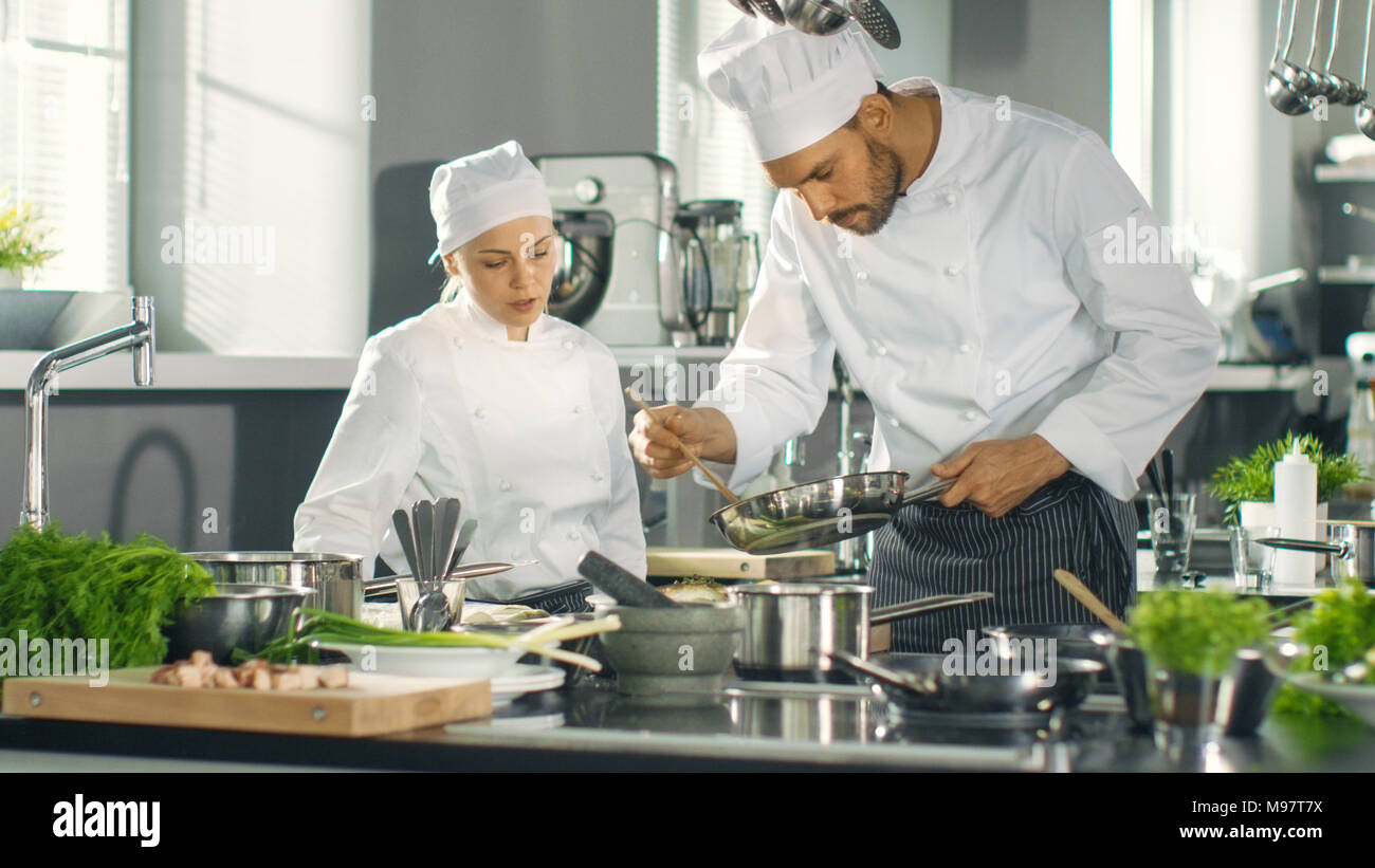Famosi Chef e la sua femmina apprendista preparare speciali piatto in un moderno ristorante a cinque stelle la cucina. Foto Stock