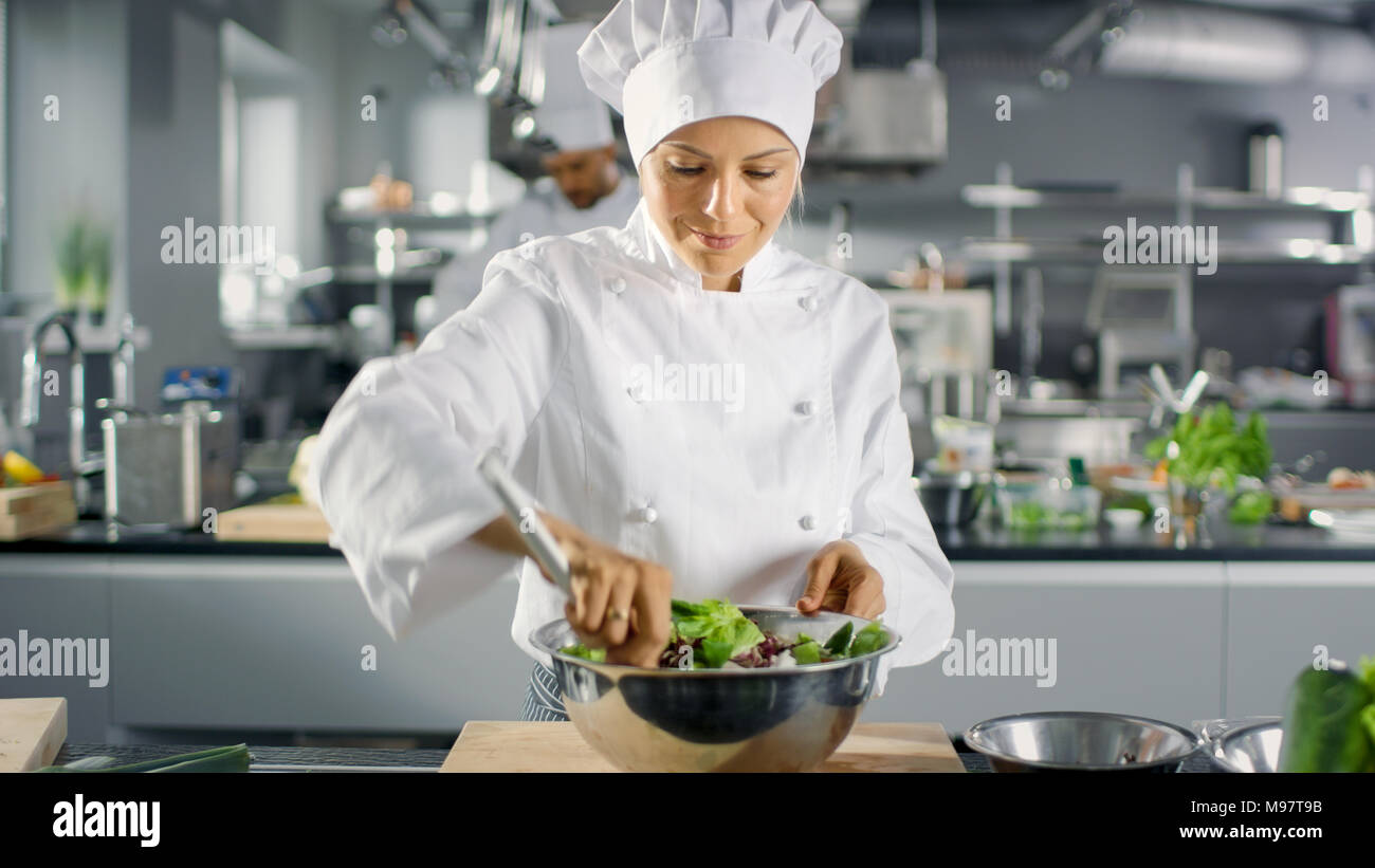 In un famoso ristorante cuoca prepara insalata. Lavora in una grande cucina moderna. Foto Stock