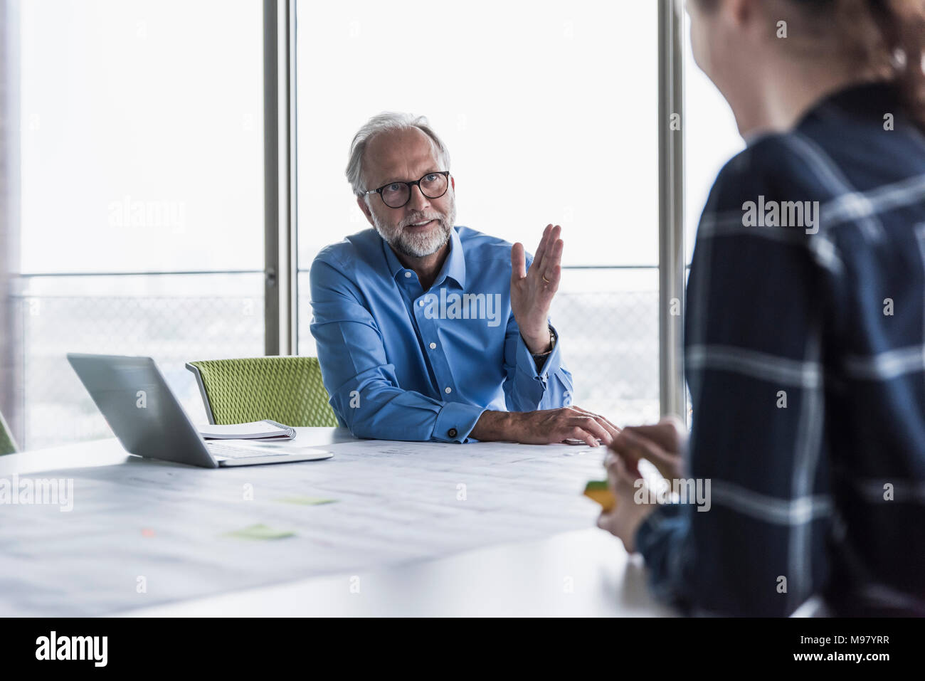 Imprenditore maturo e la giovane donna che parla nella sala conferenza in Office Foto Stock