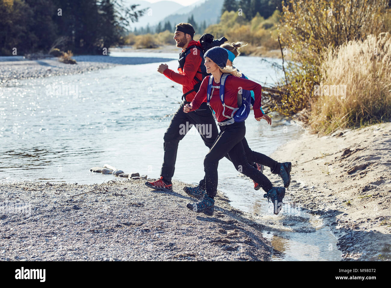 Gruppo di amici escursionismo saltando su fiume Foto Stock