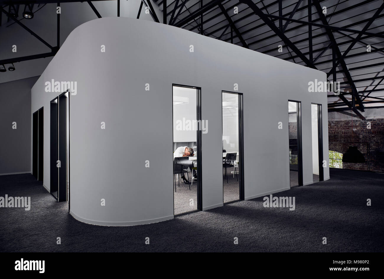 Imprenditore esausto dorme nella moderna sala conferenze Foto Stock