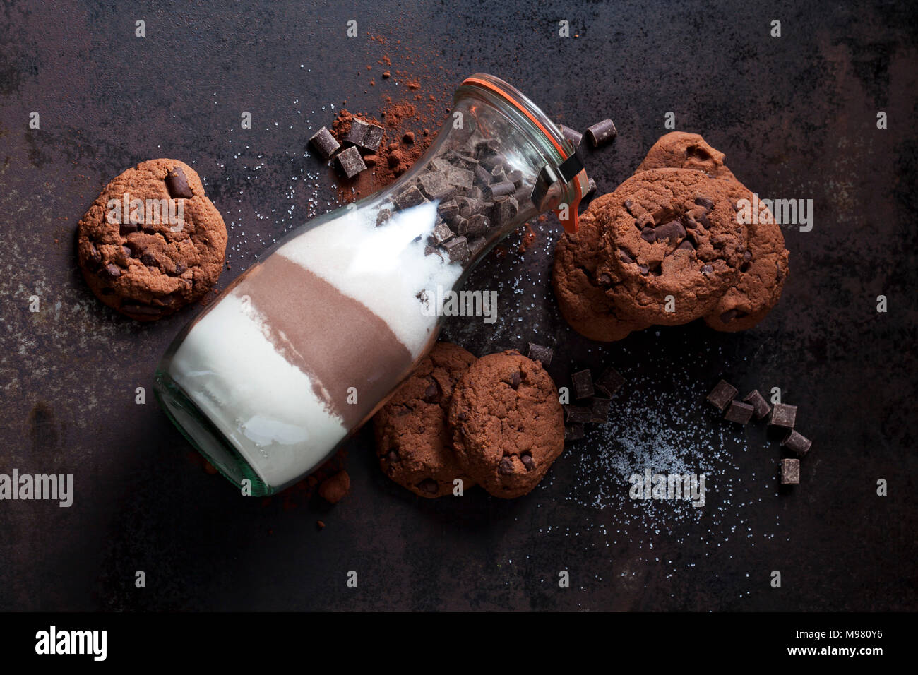 Biscotti al cioccolato e una bottiglia di vetro del mix di cottura Foto Stock