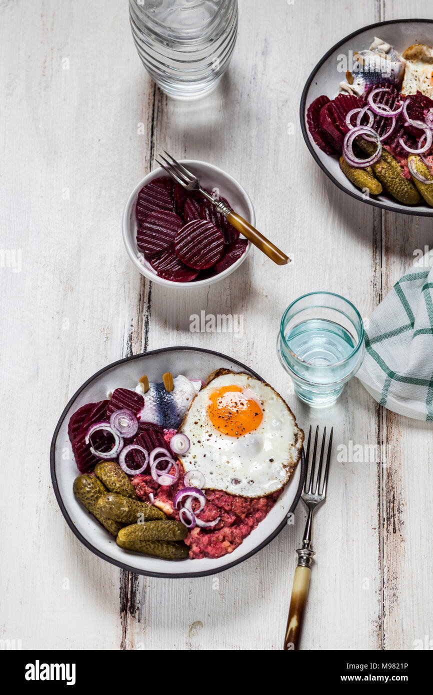 Labskaus, rollmops, cetriolino sottaceto, Insalata di barbabietole, cipolla e uovo fritto Foto Stock