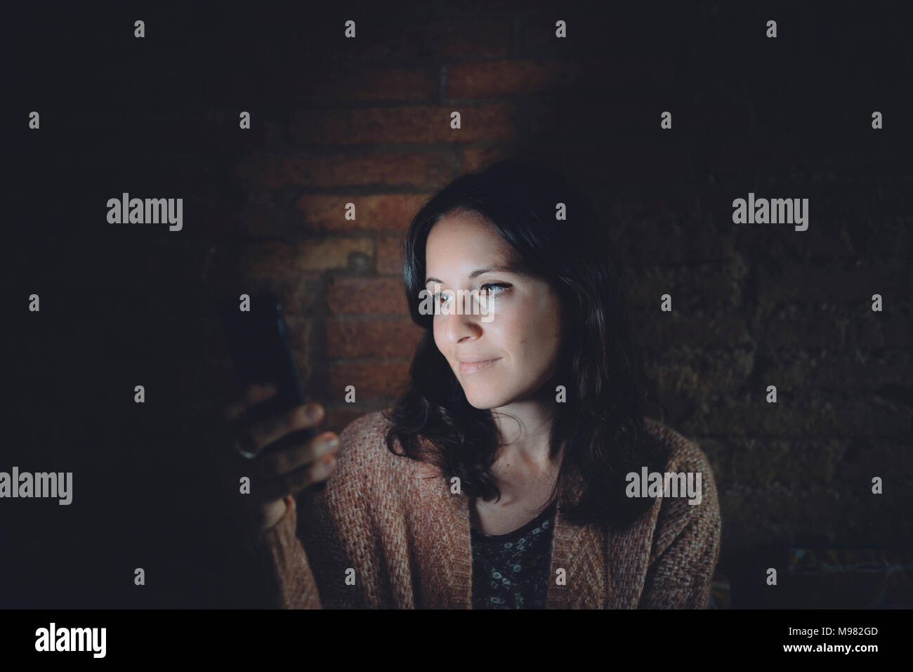 Ritratto di donna utilizza lo smartphone a casa nel buio Foto Stock