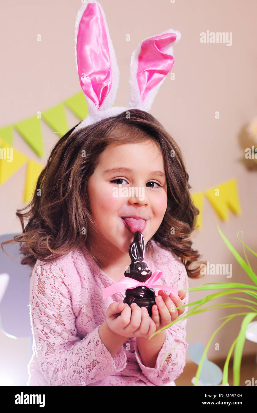 Little Baby girl lambisce un cioccolato coniglietto di Pasqua Foto Stock