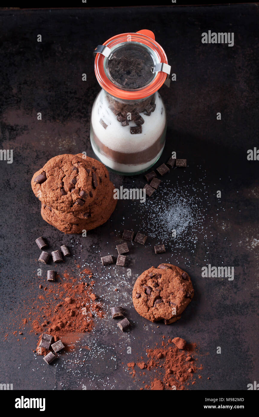 Biscotti al cioccolato e una bottiglia di vetro del mix di cottura Foto Stock