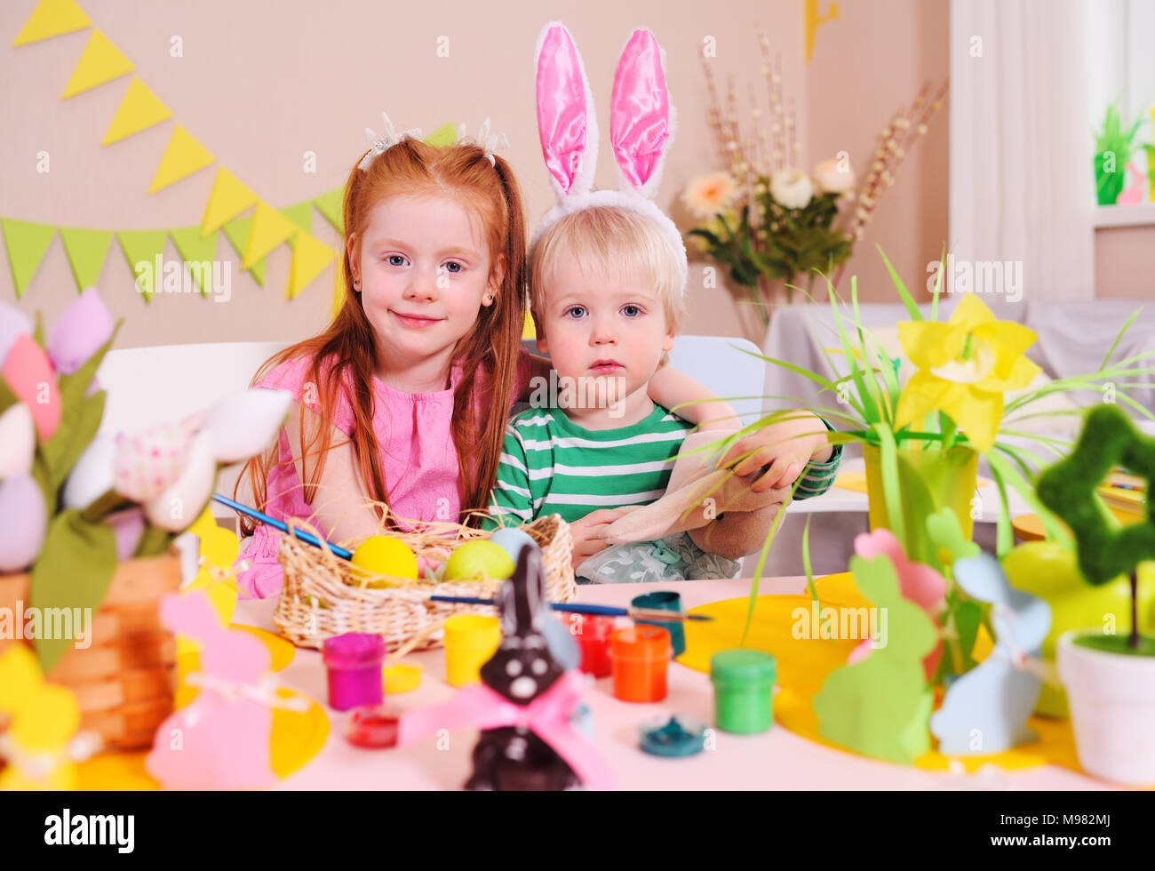 Bambini - un po' di un ragazzo e una ragazza si stanno preparando per la celebrazione della Pasqua. Fratello e Sorella di uova di vernice sullo sfondo delle decorazioni di Pasqua Foto Stock