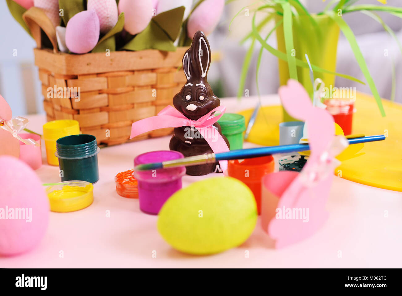 Il cioccolato coniglietto di pasqua sullo sfondo della Pasqua decor, fiori, dipinto di uova, barattoli di vernice. Preparazione per la celebrazione della Pasqua Foto Stock