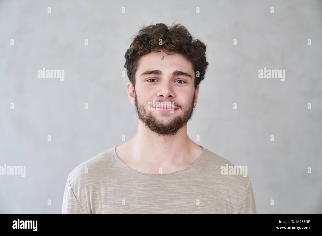 Ritratto di giovane sorridente uomo nella parte anteriore del muro grigio Foto Stock