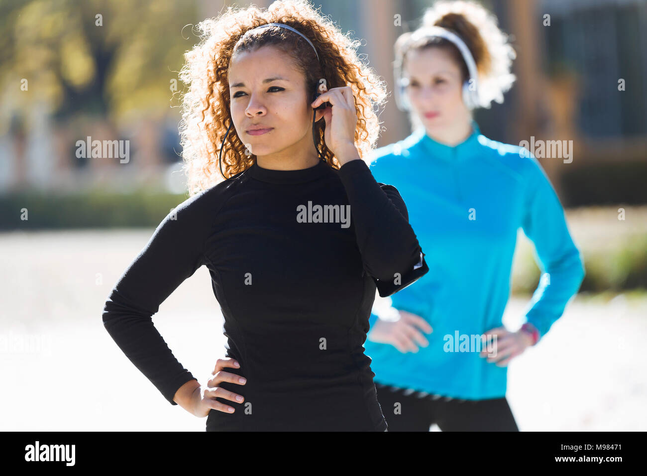 Due focalizzata sportive giovani donne piedi ascoltando la musica Foto Stock