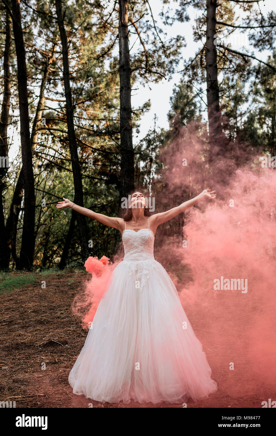 Donna che indossa abiti da sposa nella foresta circondato da nuvole di fumo Foto Stock