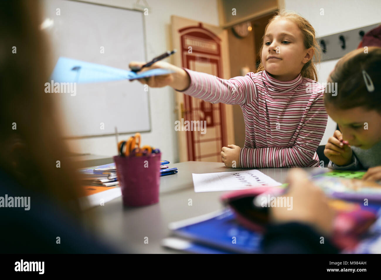 Schoolgirlhanding su foglio di carta a un compagno di classe in classe Foto Stock