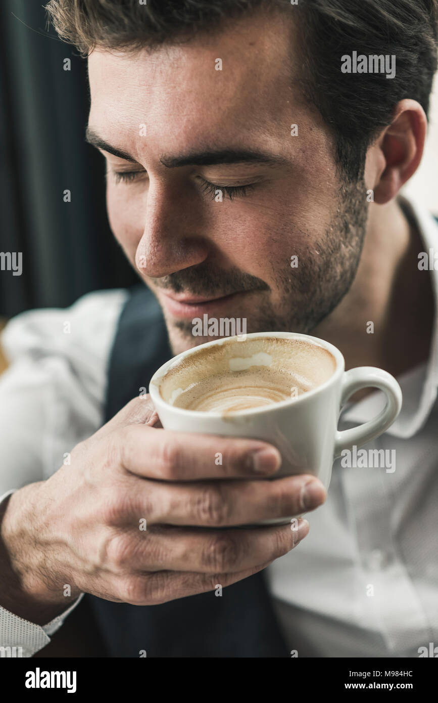 Rilassata giovane uomo bere tazza di caffè Foto Stock