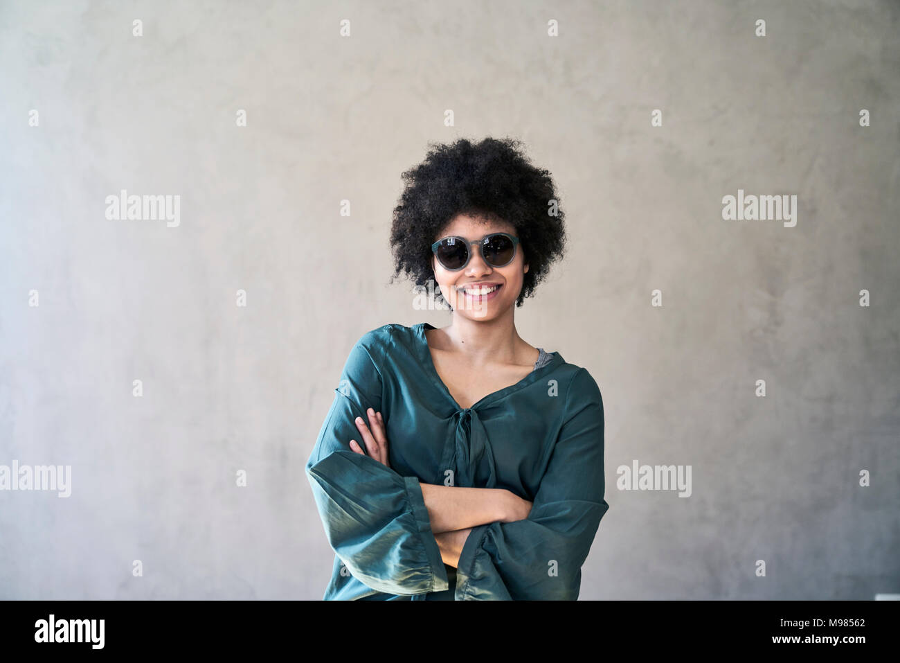 Ritratto di giovane sorridente donna che indossa gli occhiali da sole Foto Stock
