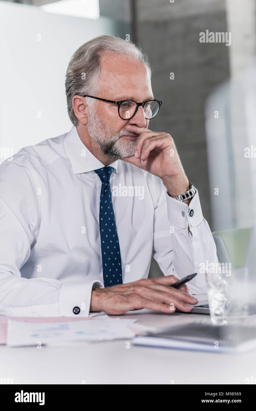 Imprenditore maturo lavorare alla scrivania in ufficio Foto Stock