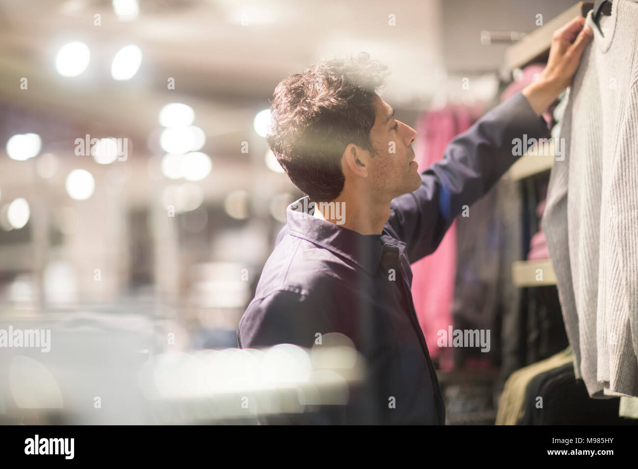 L'uomo la scelta di vestiti in negozio Foto Stock