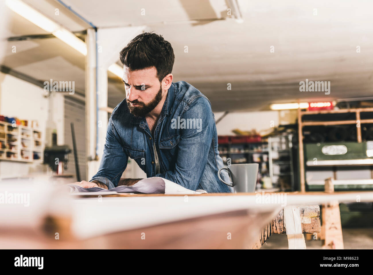 Uomo che guarda un progetto in officina Foto Stock