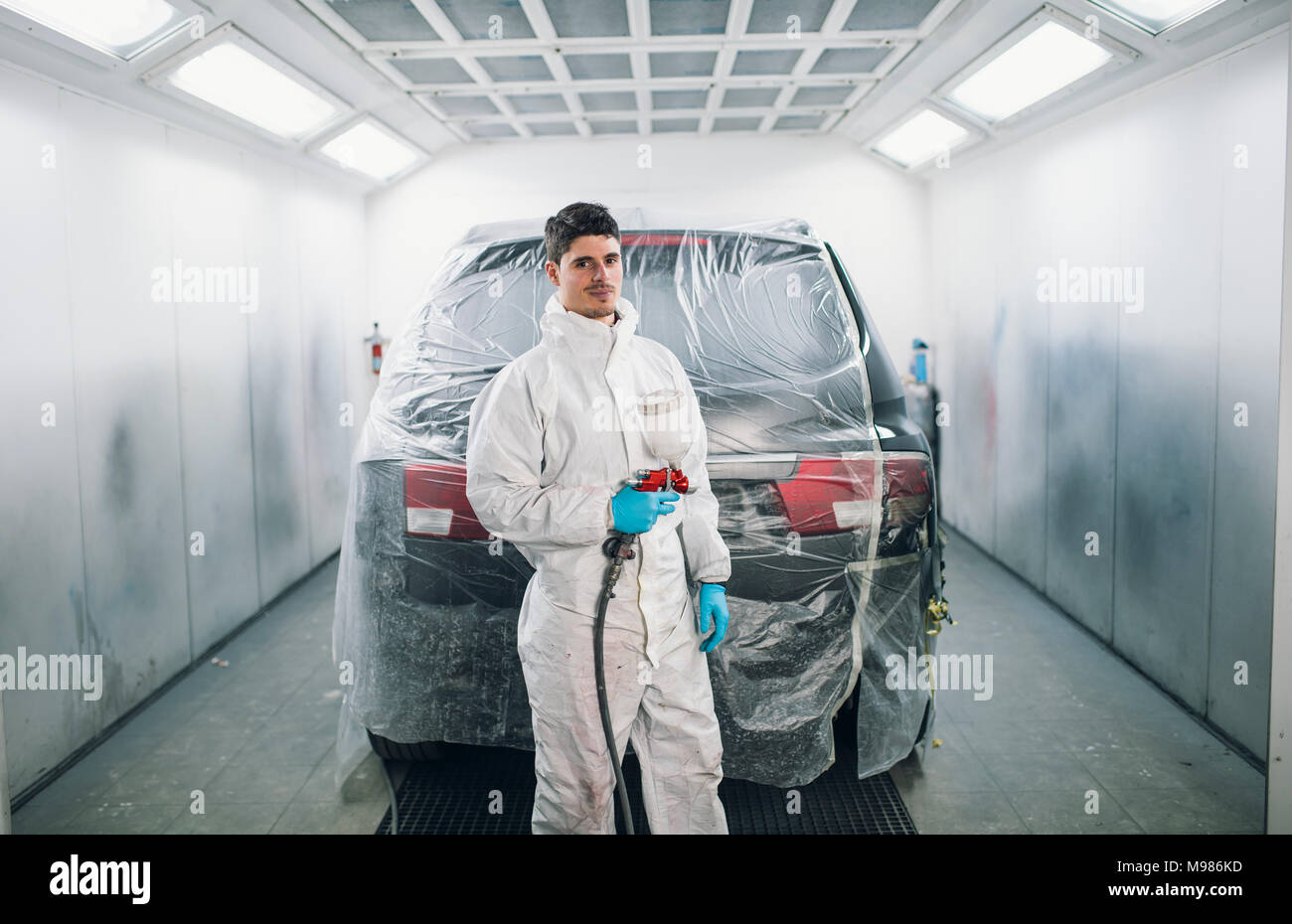 Pittore di auto con la vernice della pistola di spruzzatura Foto Stock