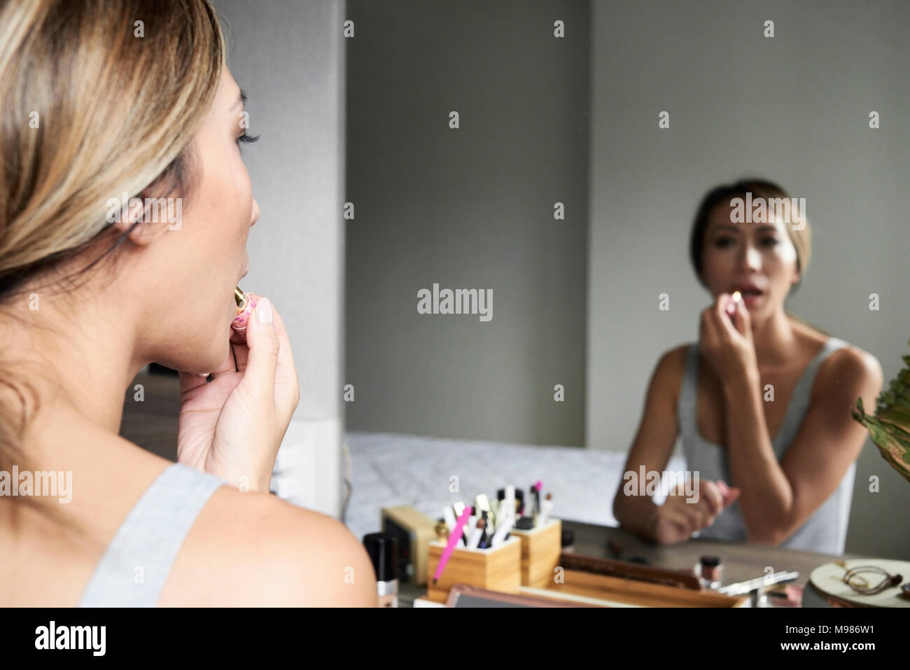 La donna di casa utilizzando il trucco rossetto di fronte a uno specchio Foto Stock