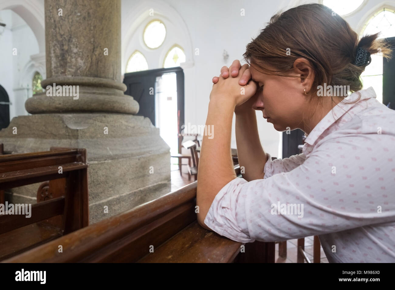 Pregando la donna cristiana in chiesa a pregare Dio per aiutare Foto Stock