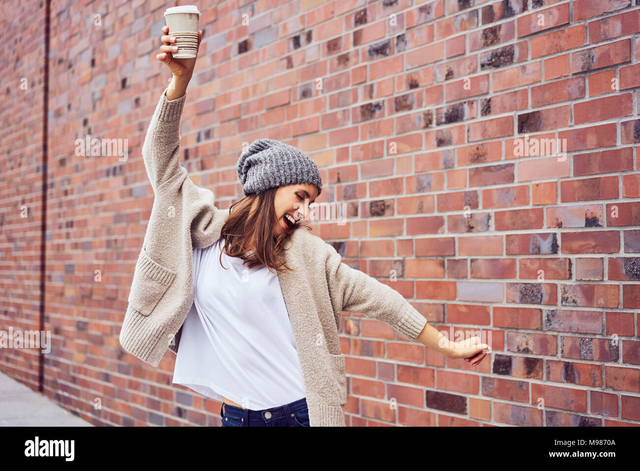 Donna felice con caffè per andare a cantare e a danzare sulla strada Foto Stock