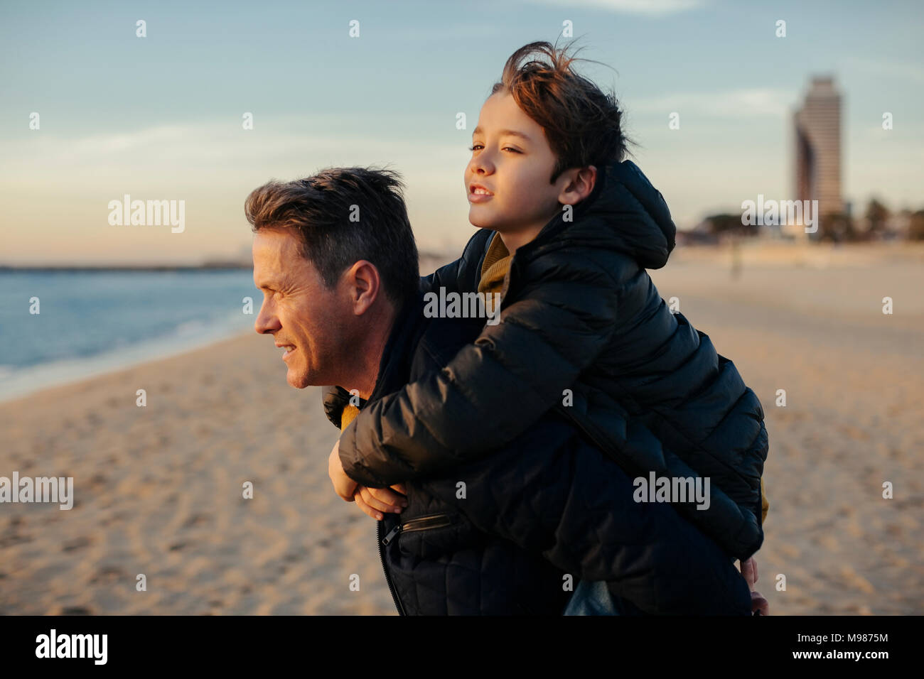 Padre figlio portante piggyback sulla spiaggia Foto Stock