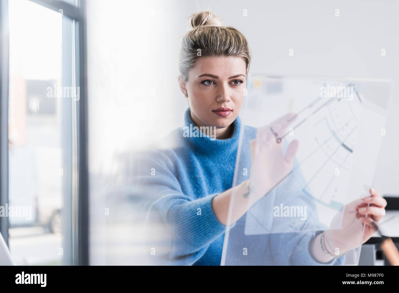 Giovane donna lavora sul design trasparente in office Foto Stock