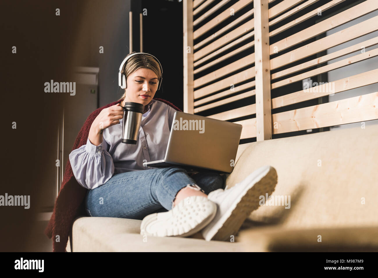 Giovane donna sul lettino con caffè e il computer portatile Foto Stock