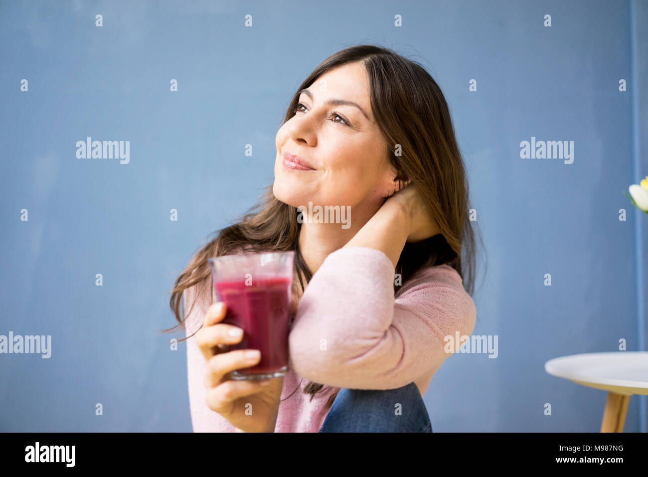 Donna sorridente holding bicchiere di succo di frutta Foto Stock