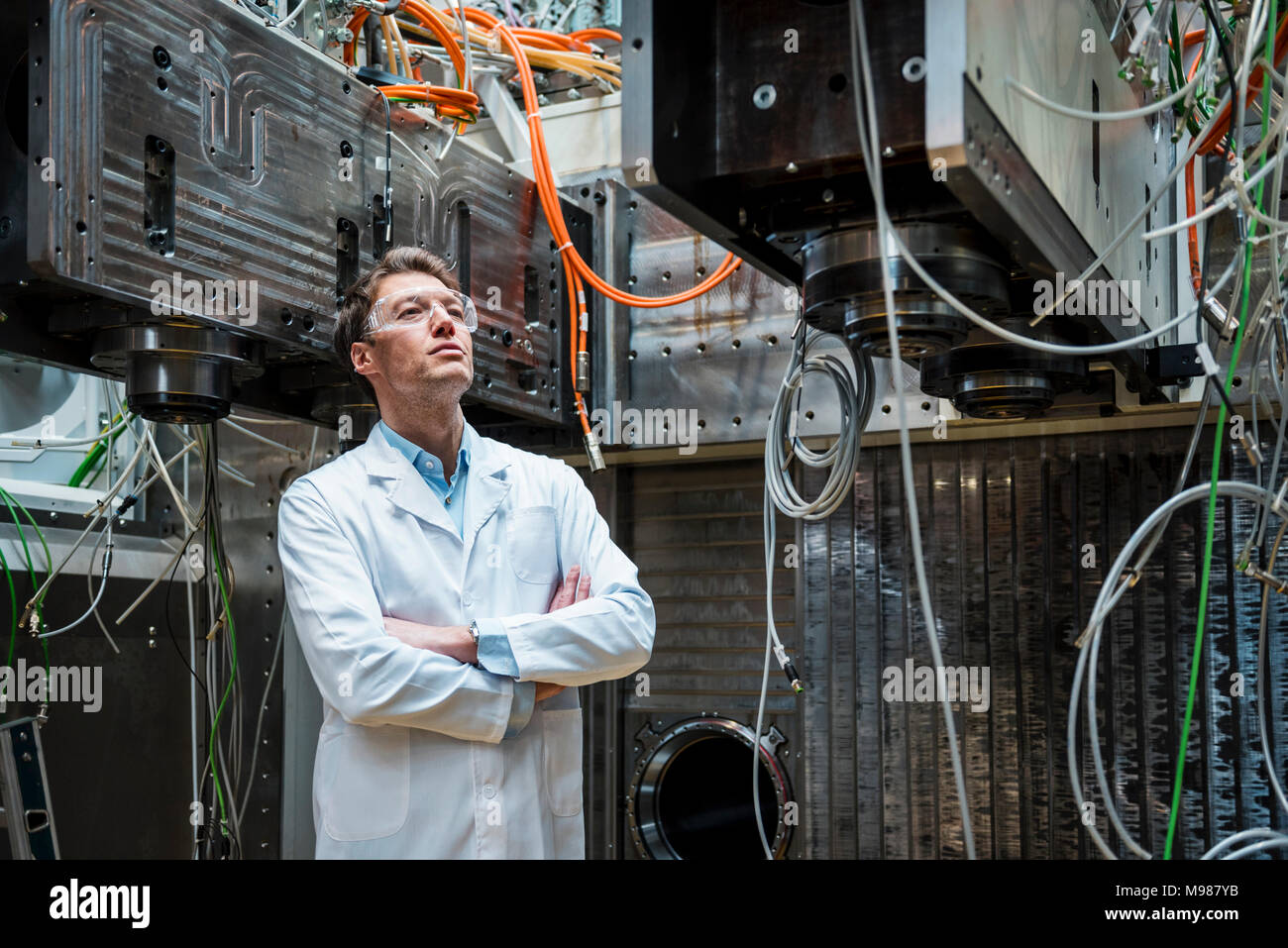 Uomo che indossa camice e occhiali di sicurezza guardando la macchina Foto Stock
