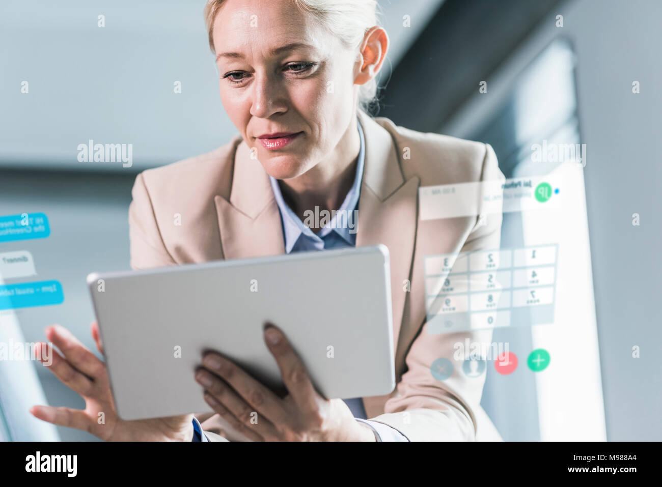 Imprenditrice seduta in ufficio utilizzando la tavoletta digitale Foto Stock