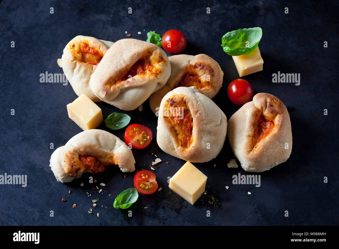 Pizza le ciambelle glassate, pomodori ciliegini, il formaggio a dadini e le foglie di basilico Foto Stock