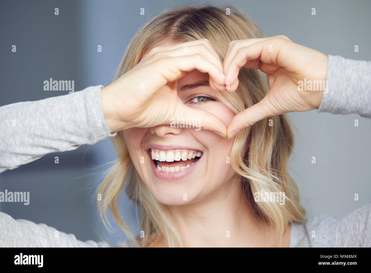 Ritratto di donna ridere la costruzione di cuore con le dita Foto Stock
