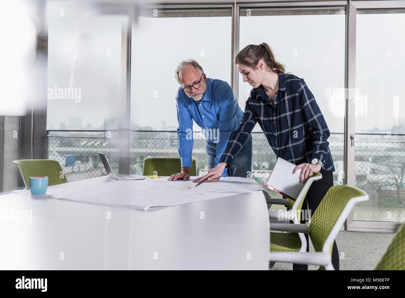 Imprenditore maturo e la giovane donna che parla nella sala conferenza in Office Foto Stock