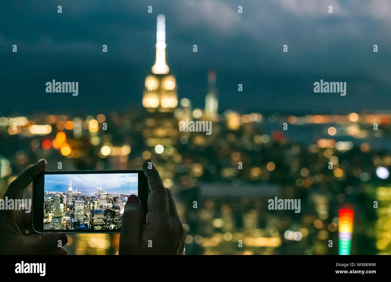 Stati Uniti d'America, donna mani smartphone durante lo scatto di una foto di Manhattan di notte Foto Stock