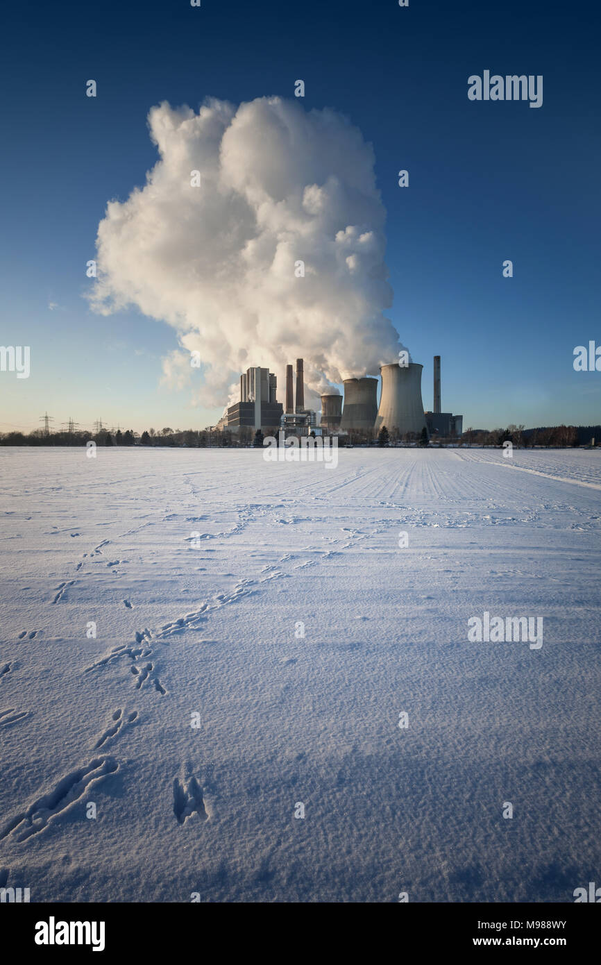 Impianto alimentato a carbone Weisweiler d'inverno. Il vapore passando dai refrigeratori. Coperte di neve campo in primo piano. Foto Stock