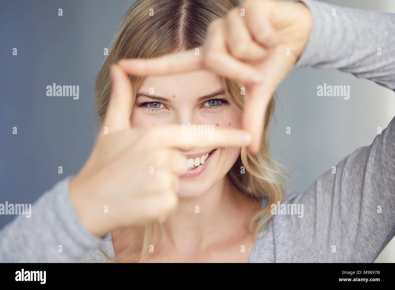 Ritratto di donna ridere la costruzione di telaio con le dita Foto Stock