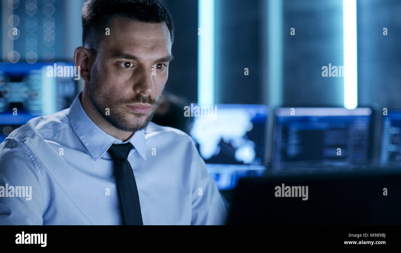 Professional Controller tecnico con i colleghi sulle loro workstation. Sono in Sala di monitoraggio con più monitor che li circondano. Foto Stock