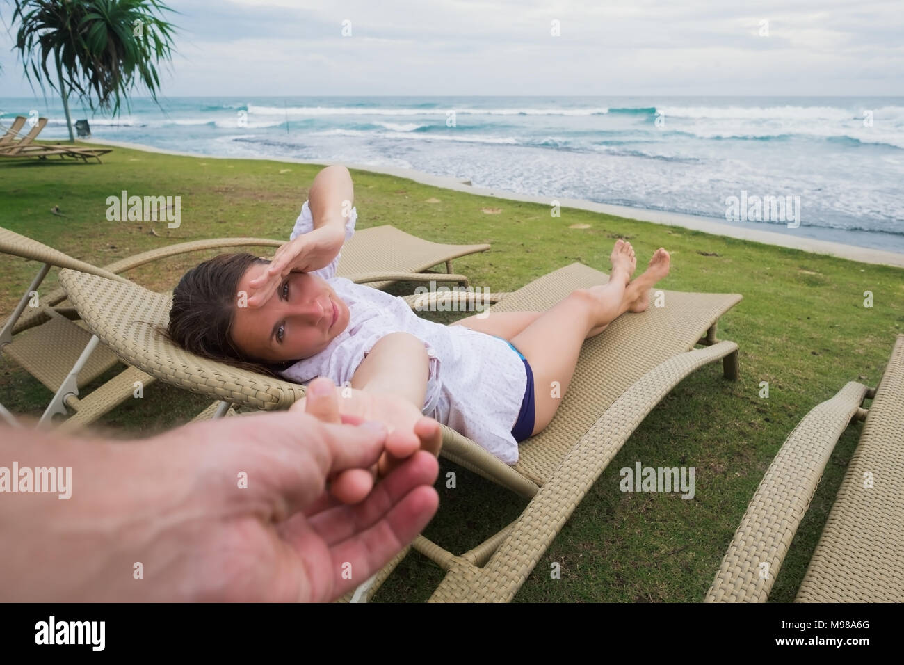 La donna caucasica nella poltrona vicino spiaggia tenendo il marito mano. Follow me concetto. Avendo una grande vacanza vicino al mare in hotel Foto Stock