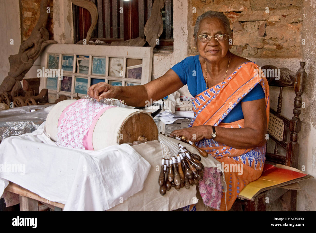 Un felice sorridente donna femmina artigiano dello Sri Lanka lavoratore rendendo Beeralu pizzo gli elementi di tessitura utilizzando i metodi tradizionali presso il Museo Nazionale di Galle Foto Stock