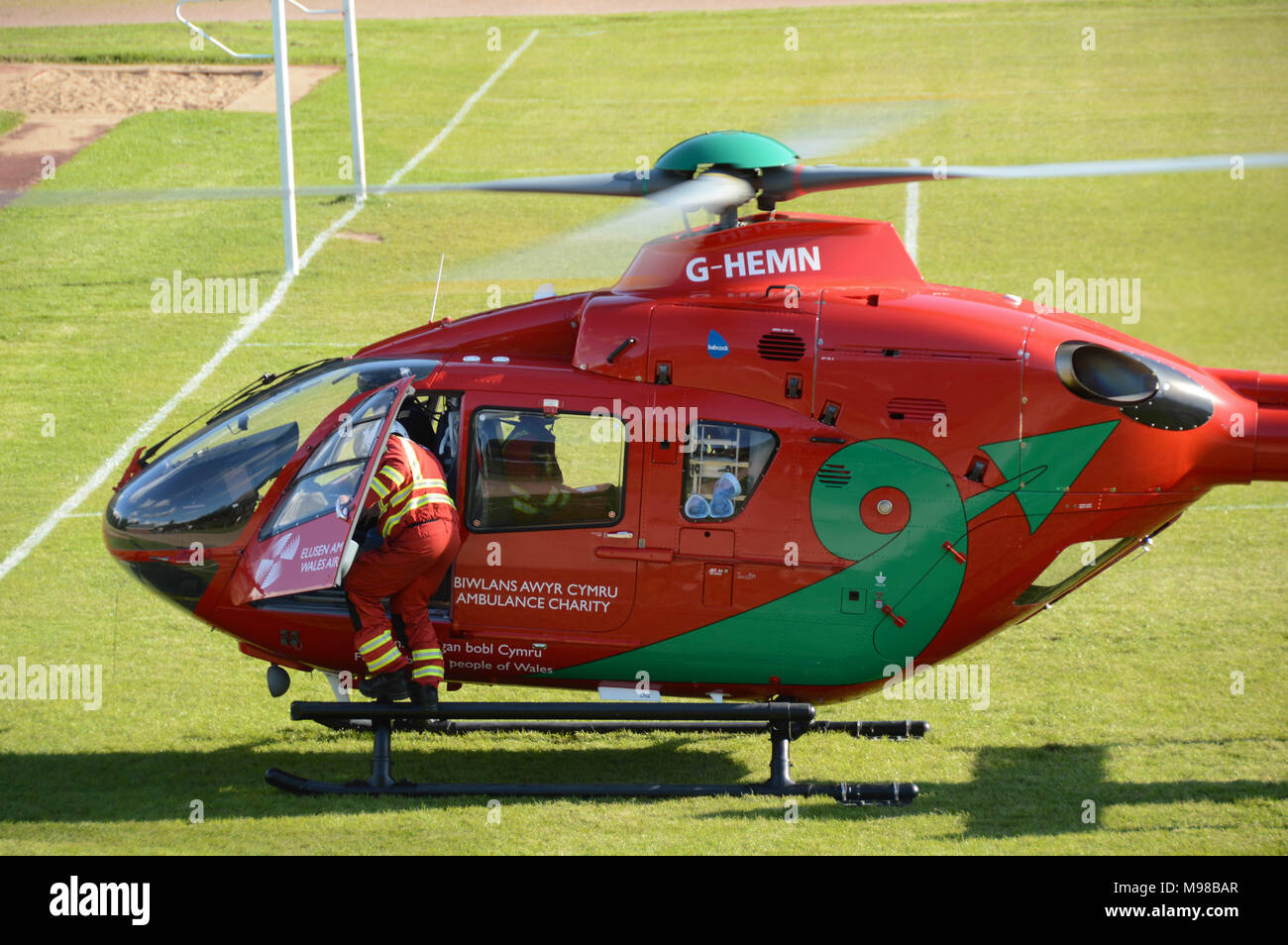 Un membro di equipaggio si arrampica nel cockpit di un Airbus elicottero del Galles Air Ambulance Service prima che decolla Foto Stock
