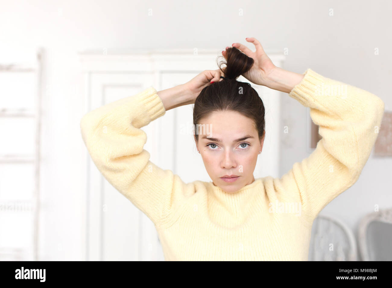 Donna informale rendendo acconciatura guardando la fotocamera Foto Stock