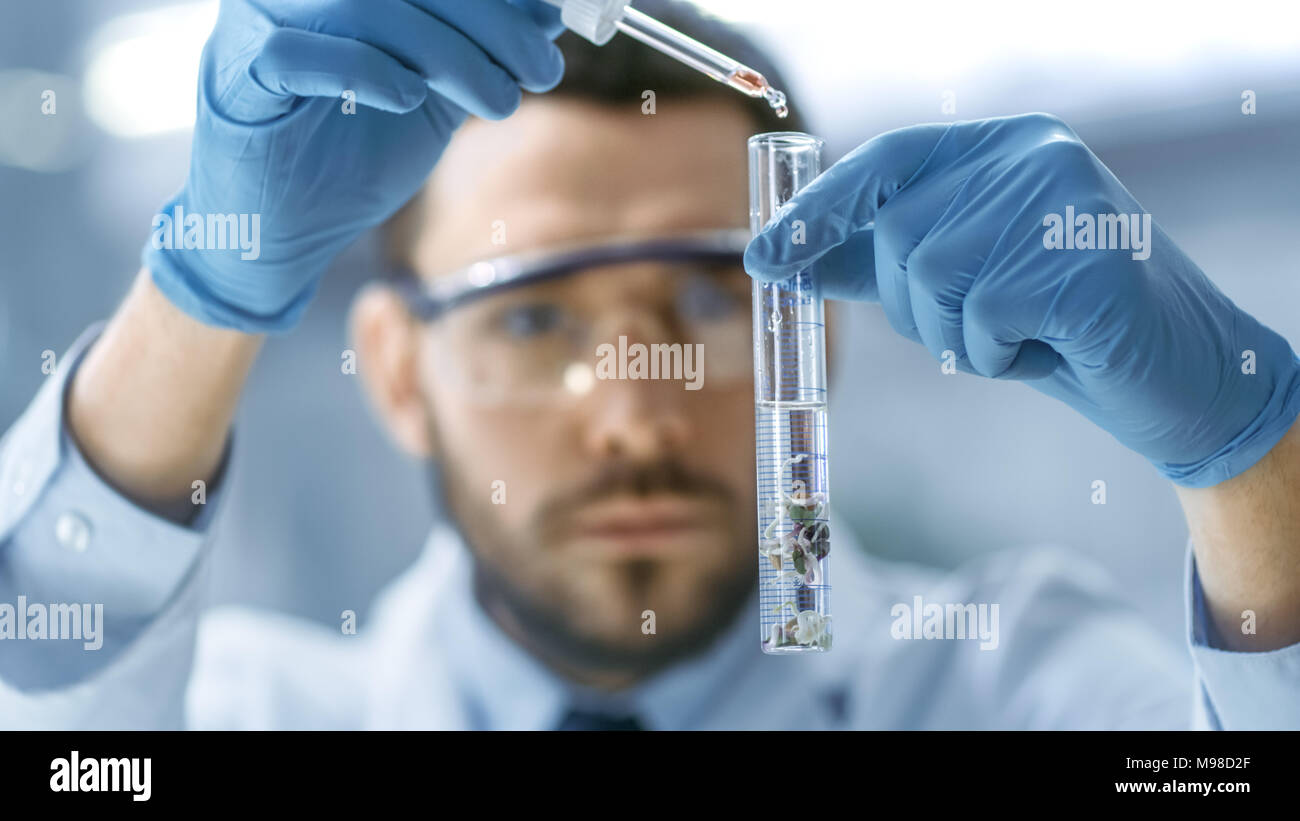 In un moderno laboratorio di uno scienziato conduce esperimenti mediante gocciolamento in una provetta con impianto modificato. Foto Stock