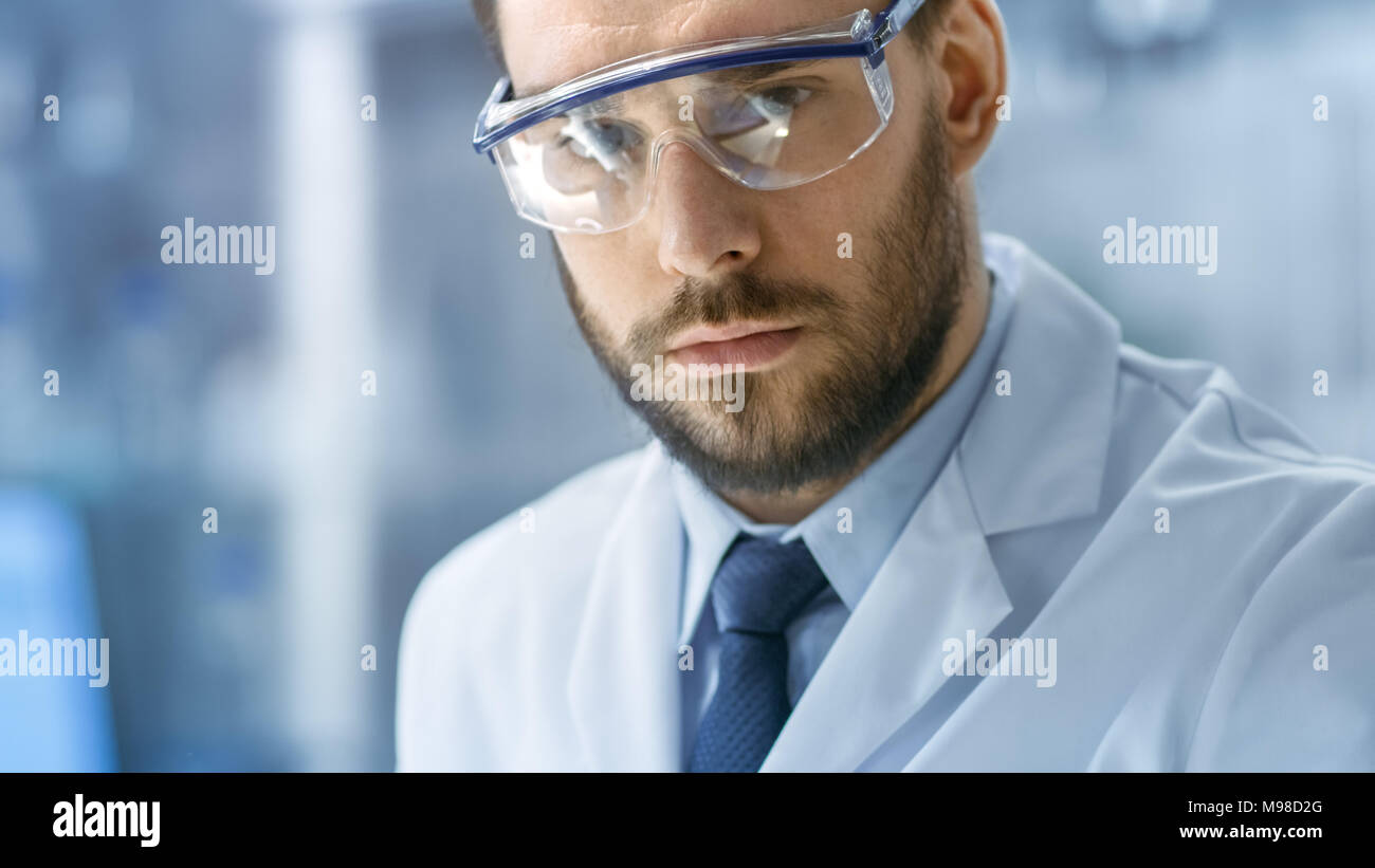 Close-up faccia colpo di scienziato che lavora e guardando nella telecamera in un moderno laboratorio. Foto Stock