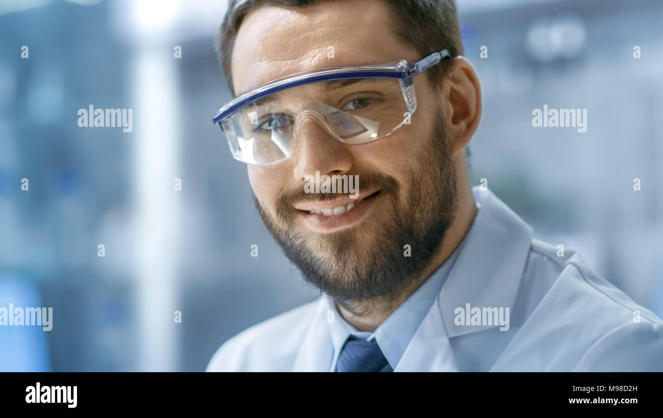Close-up shot di scienziato volto alla ricerca e sorridente nella fotocamera in un moderno laboratorio. Foto Stock